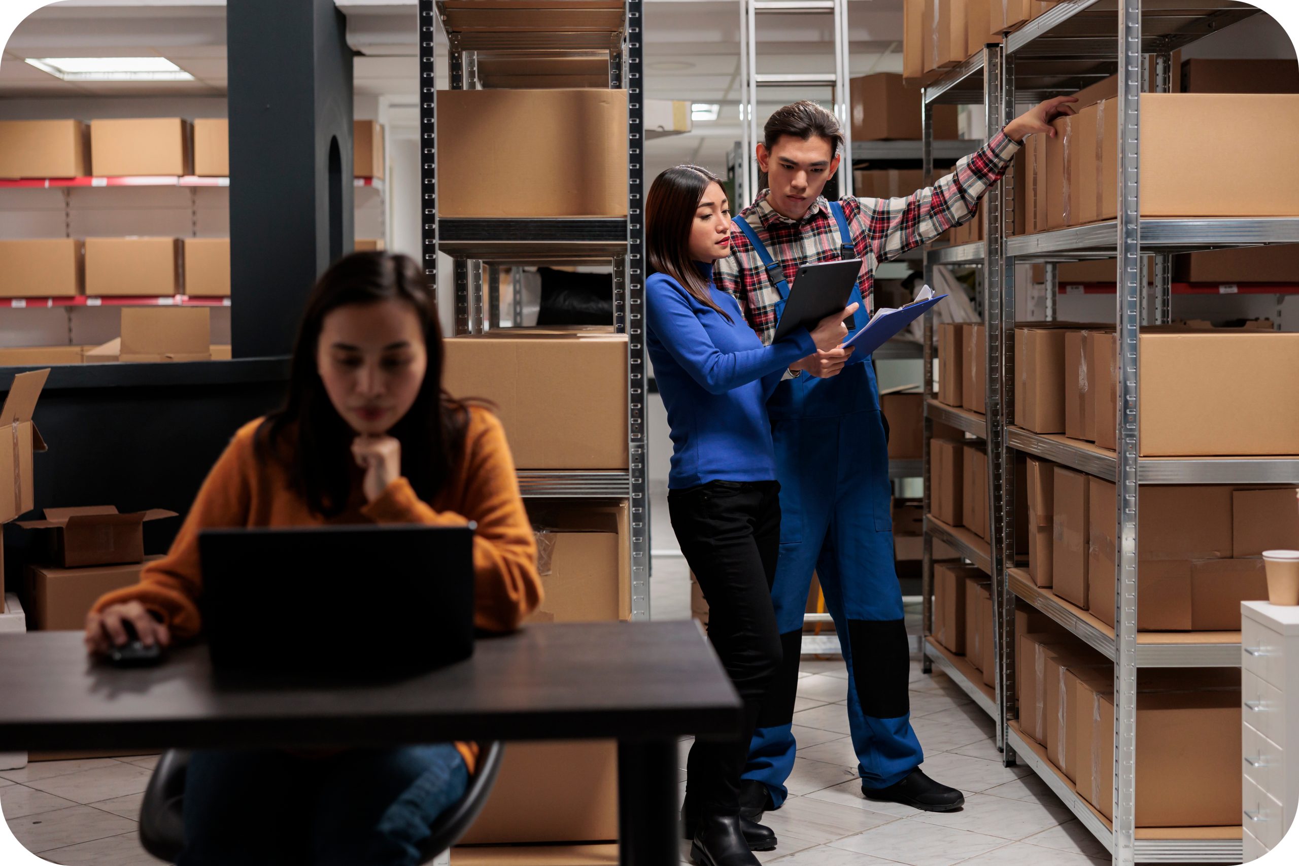 Warehouse team reviewing inventory checklist among shelved boxes
