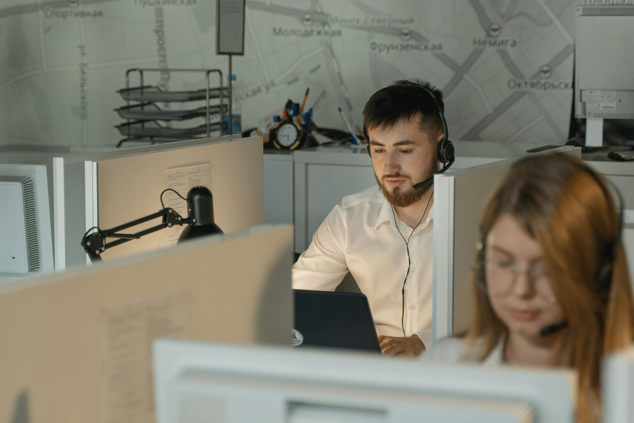 IT support specialist at workstation wearing headphones with microphone.